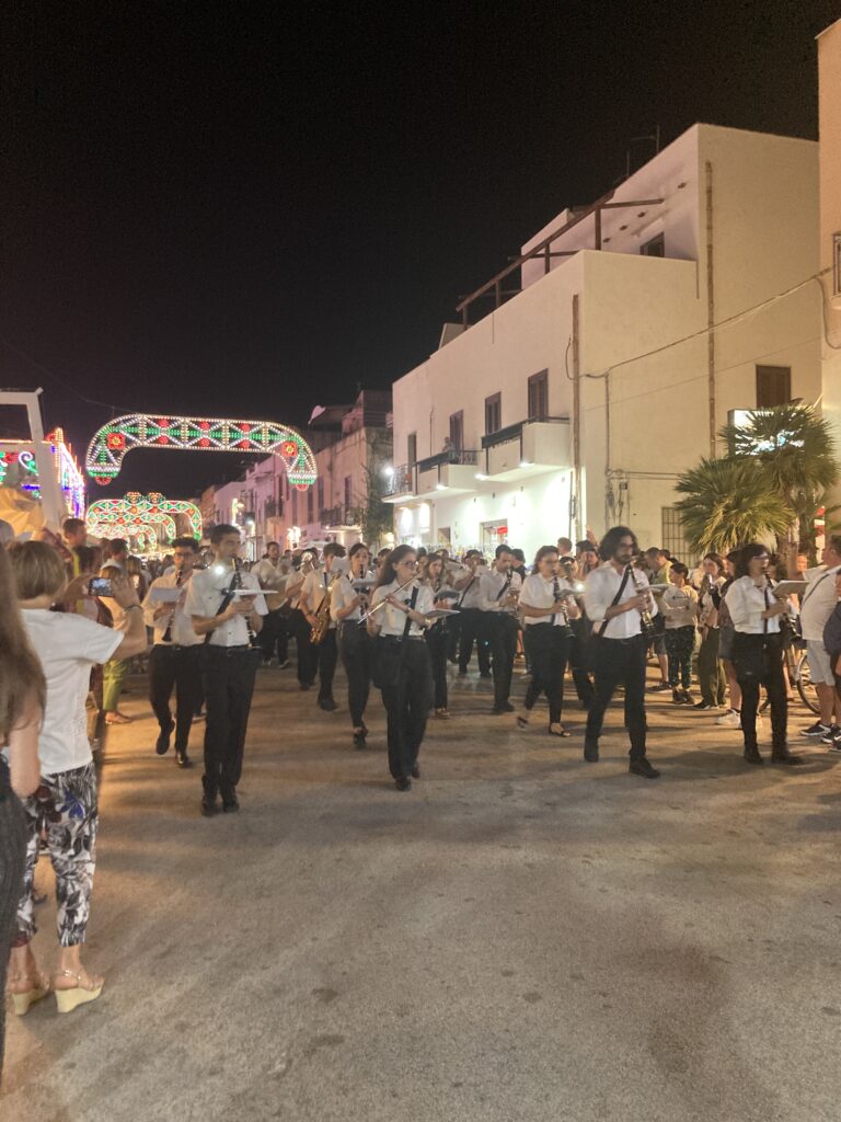 Musikkapelle während eines nächtlichen Festumzugs bei der Festa di San Vito Martire in den beleuchteten Straßen von San Vito Lo Capo.